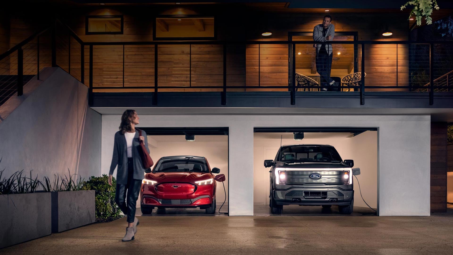 Woman walking out from home garage with a 2024 Mustang® Mach-E and Ford Lightning® truck in plugged-in and charging | Matthews-Currie Ford in Nokomis FL